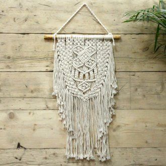 Décoration murale en macramé écru sur mur en bois