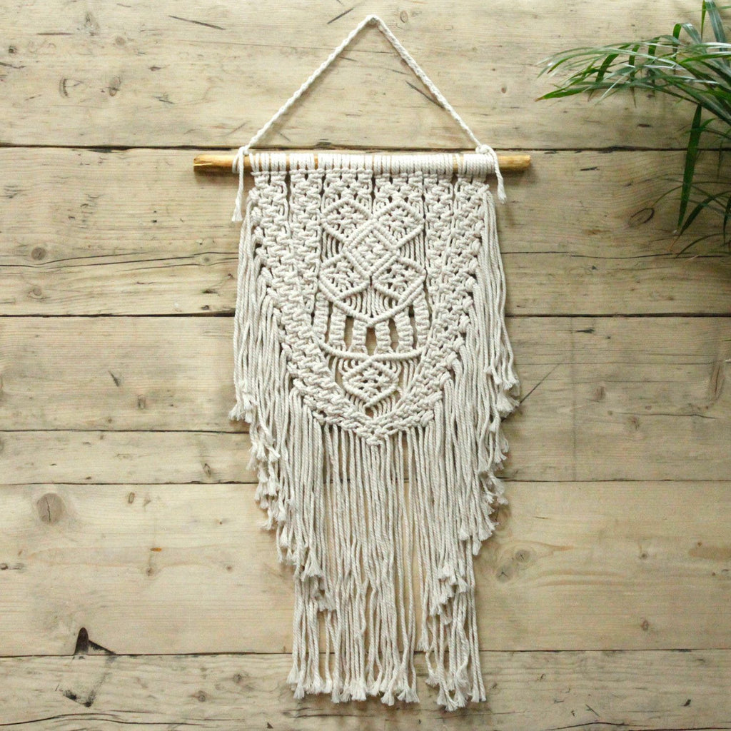 Décoration murale en macramé écru sur mur en bois